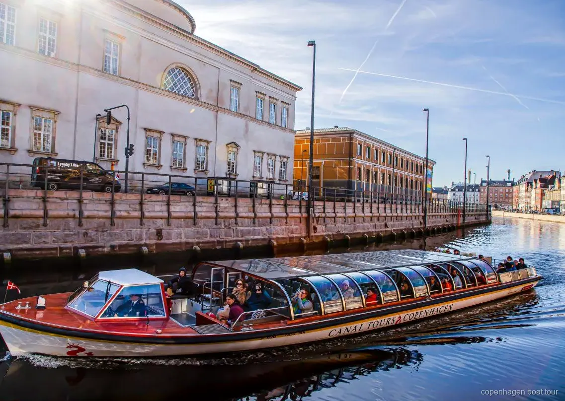 Copenhagen canal tour boat sailing past historic waterfront buildings near Ved Stranden