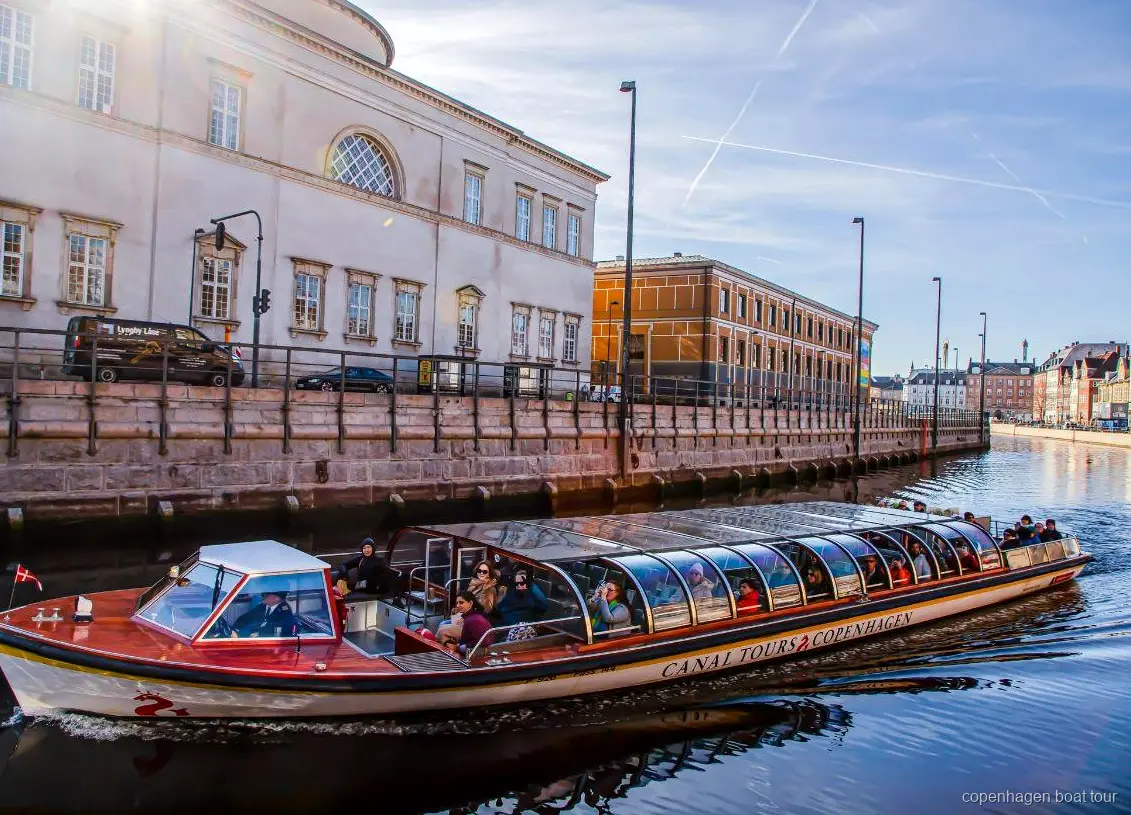 Kanalrundfart i København sejler forbi historiske vandkantsbygninger nær Ved Stranden