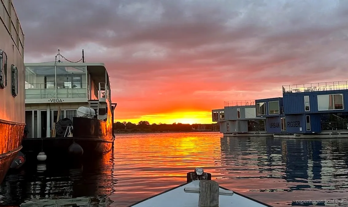 Privater Kapitän steuert eine Kopenhagen private Bootstour an Wasserfrontgebäuden vorbei